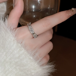 Gros plan d'une bague en argent sertie de zircons et perles sur un doigt féminin