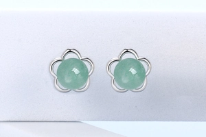 Macro detail of silver flower earrings with green aventurine beads on white stand