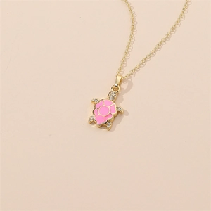 Detail of gold-plated turtle pendant with pink enamel shell and sparkling crystals
