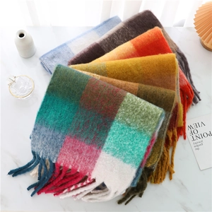 Detail shot of colorful plaid scarves with soft fringe on white marble background
