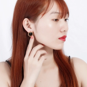 Fashionable black crystal stud earring with gold bead edge shown on a model