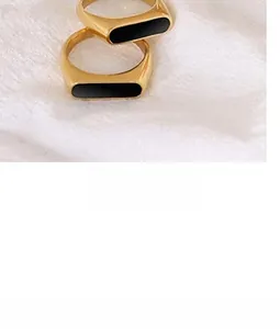 Close-up of minimalist gold-plated titanium steel rings with black rectangular inlay on fabric