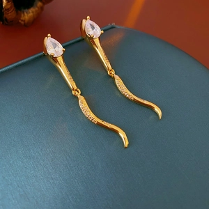Macro shot of long gold earrings with pear-cut zircon and curved diamond accents