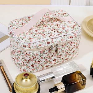 Floral makeup bag with top handle and double zipper closure on a vanity desk
