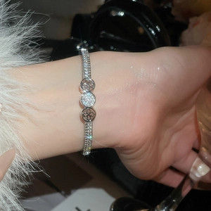 Close-up of silver-tone zircon bracelet with clover motifs on a person's wrist