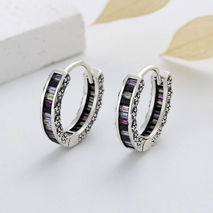 Macro detail of S925 silver earrings with black and purple zircon stones and carved patterns
