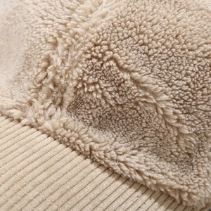 Detailed close-up of khaki sherpa and corduroy fabric stitching on a warm baseball cap