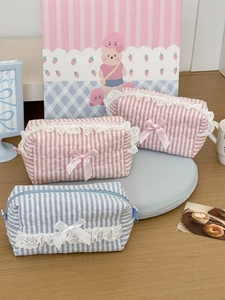 Trousses de maquillage matelassées à rayures pastel avec dentelle sur table en bois