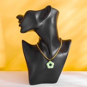 Golden titanium steel necklace with green five-leaf flower pendant on a model
