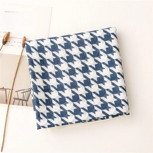 Flat lay of blue houndstooth scarf folded next to a magazine and dried flower