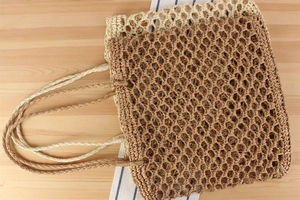 Detail of beige and brown hollow out woven straw handbags on a rustic wooden table