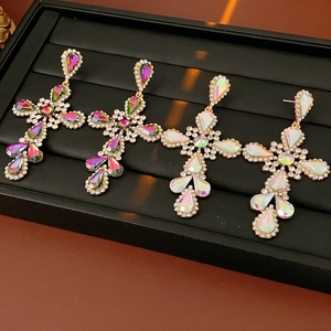 Close-up of vintage gold cross earrings with colorful crystal and rhinestone details