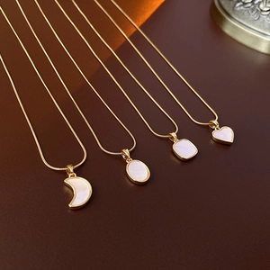 Vue détaillée de colliers dorés avec pendentifs lune, cœur et nacre sur fond noir