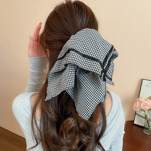 Detail of vintage black and white plaid bow hair tie on a classic ponytail hairstyle
