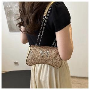 Shoulder bag with gold sequins, metal bow detail and chain strap on a model back