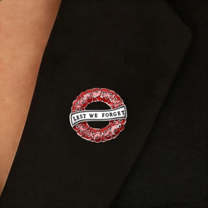 Macro detail of poppy wreath brooch with Lest We Forget text on black blazer lapel