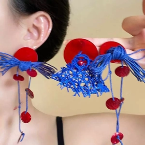 Boucles d'oreilles bohèmes à pompons rouges et bleus avec design tissé sur mannequin