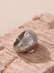Detailed close-up of polished silver steel ring with engraved heart pattern on stone