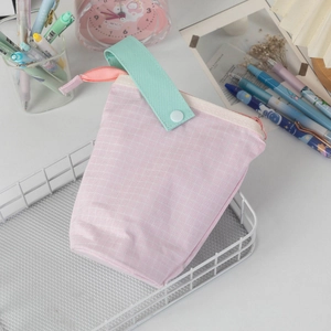 Detailed view of pink plaid pencil case with a mint green handle on a mesh tray