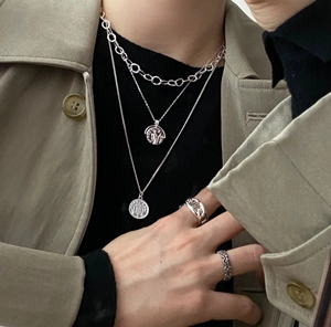 Close-up of layered 925 sterling silver necklaces and chain rings on a model