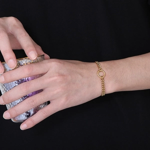 Fashionable gold stainless steel double chain bracelet with circle charm on female model