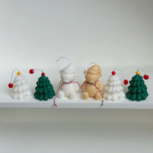 Detailed view of mini Christmas tree and bear candles on a white shelf for festive decor