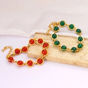 Elegant gold beaded bracelets with vintage red and green stones on textured stones