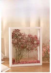 Detail of white hollow wooden photo frame with preserved pink dried flowers for home decor