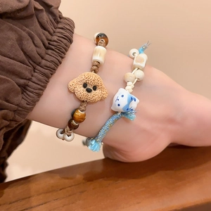 Detail of handmade ceramic cat and puppy beads on woven rope bracelets for women