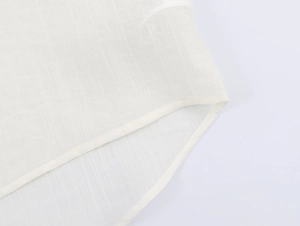 Detailed close-up of curved hem and stitching on cream textured cotton shirt