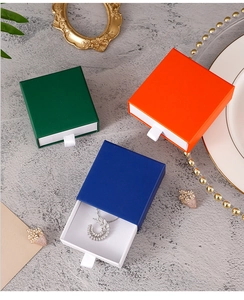 Three-color drawer jewelry boxes in green, orange, and blue with white ribbon pull cords