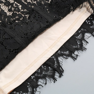 Dettaglio in primo piano del pizzo floreale nero con bordo a ciglia e fodera beige