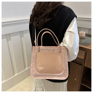 Détail d'un sac en peluche rose avec broderie papillon et texture en similicuir lisse