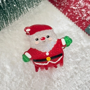 Close-up of a Santa Claus hair claw clip with glitter finish on festive Christmas decor