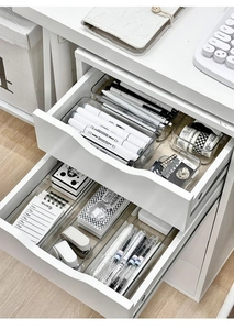 Close-up of white desk drawers with clear acrylic organizers for stationery storage