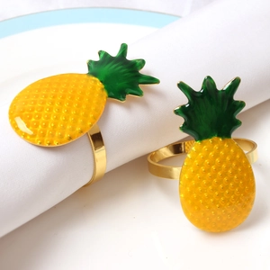 Detail of yellow pineapple napkin rings with green leaves and gold metal holders