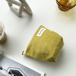 Macro shot of yellow corduroy makeup bag with Big Star Little Moon label on a desk