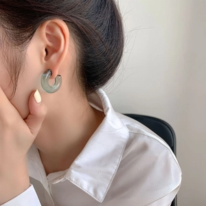 Close-up of a translucent teal C-shaped hoop earring worn for a minimalist office style