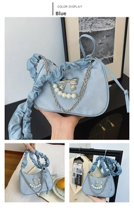 Detail of light blue crescent bag with silver bow pendant and pearl chain decoration