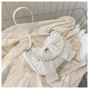 Detail of white jacquard fabric bag with bow ornament and elegant pearl handle