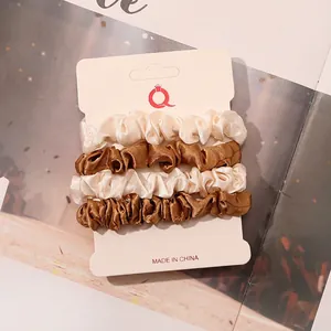 Detail of 4-piece satin scrunchies set in beige and bronze on a white display card