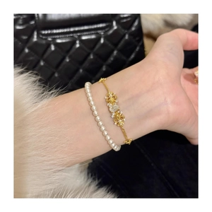 Close-up of gold iris flower chain bracelet with sparkling zircon and pearl stacking