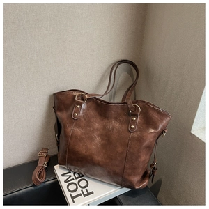 Detail of dark brown leather tote bag with metal rings, studs and a detachable shoulder strap