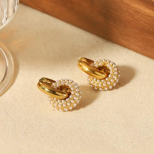 Close-up of 18k gold interlocking hoop earrings featuring white micro pearl inlay