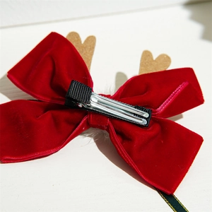 Detail of red velvet Christmas bow clip with reindeer antlers and metal duckbill clasp