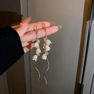 Close-up of Lily of the Valley earrings with white petals and pink crystal beads