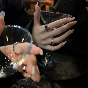 Minimalist geometric black zircon ring with woven texture shown on hand with martini glass