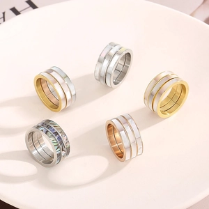 Close-up of stacked stainless steel rings with Roman numerals and shell inlays on a tray