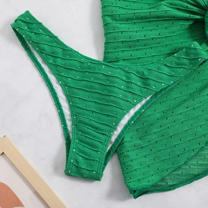 Close-up of bright green textured knit bikini fabric on a white marble surface
