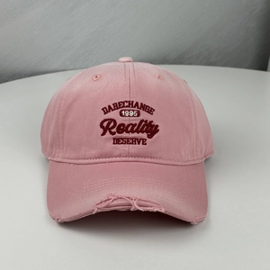 Close-up of distressed brim details and 3D embroidery on pink vintage baseball cap